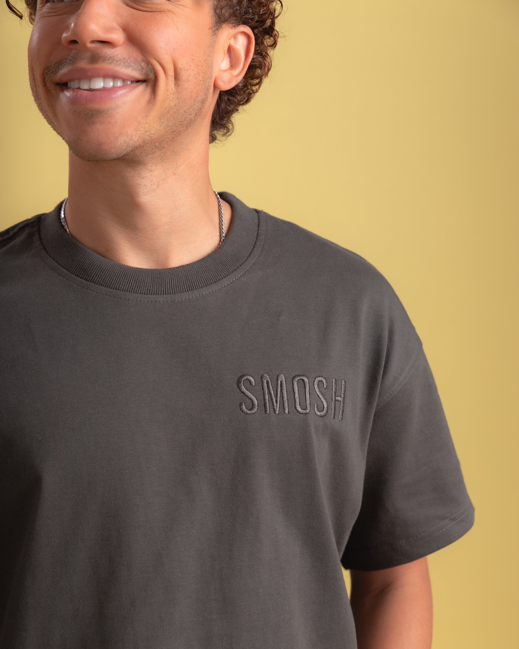 Man wearing a dark gray t-shirt with 'SMOSH' logo on a yellow background