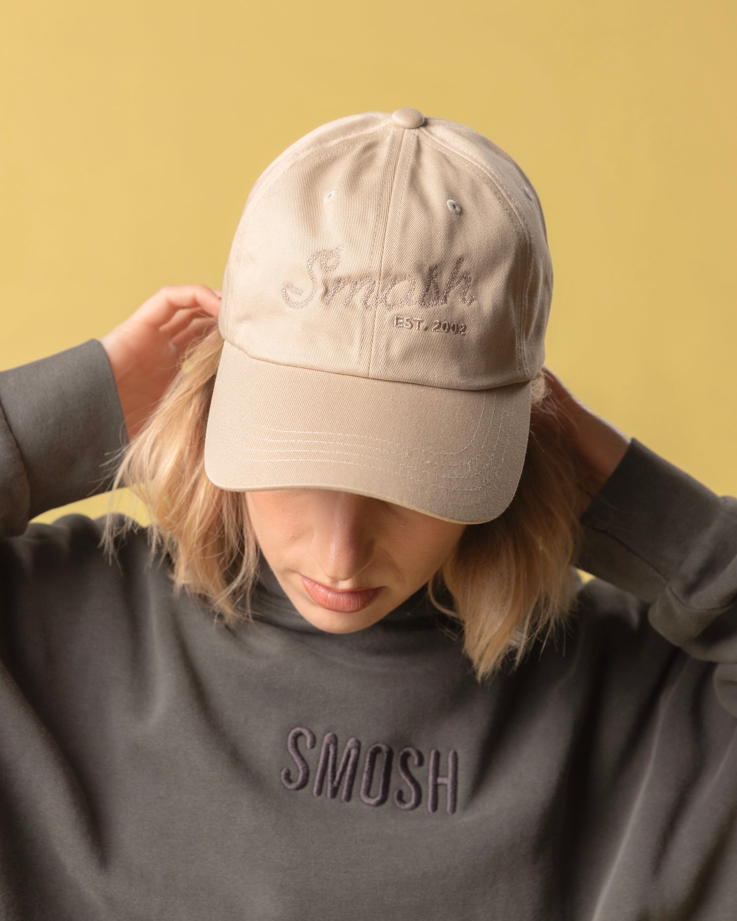 girl wearing cream colored hat that says smosh est. 2002