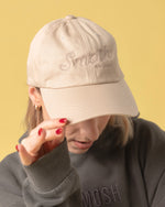 girl wearing cream colored hat that says smosh est. 2002