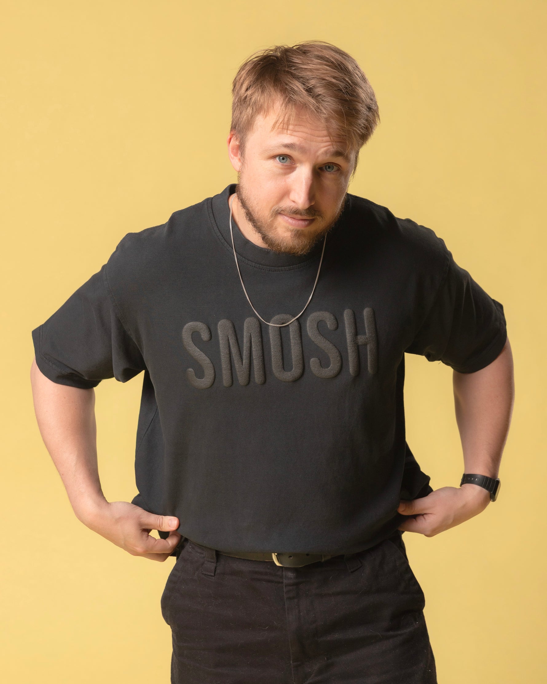 Person wearing a black shirt with 'SMOSH' text on a yellow background