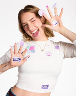 Person wearing multiple stickers on their hands and shirt against a white background