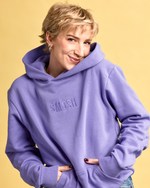 Person wearing a purple hoodie with 'SMOSH' logo on a yellow background