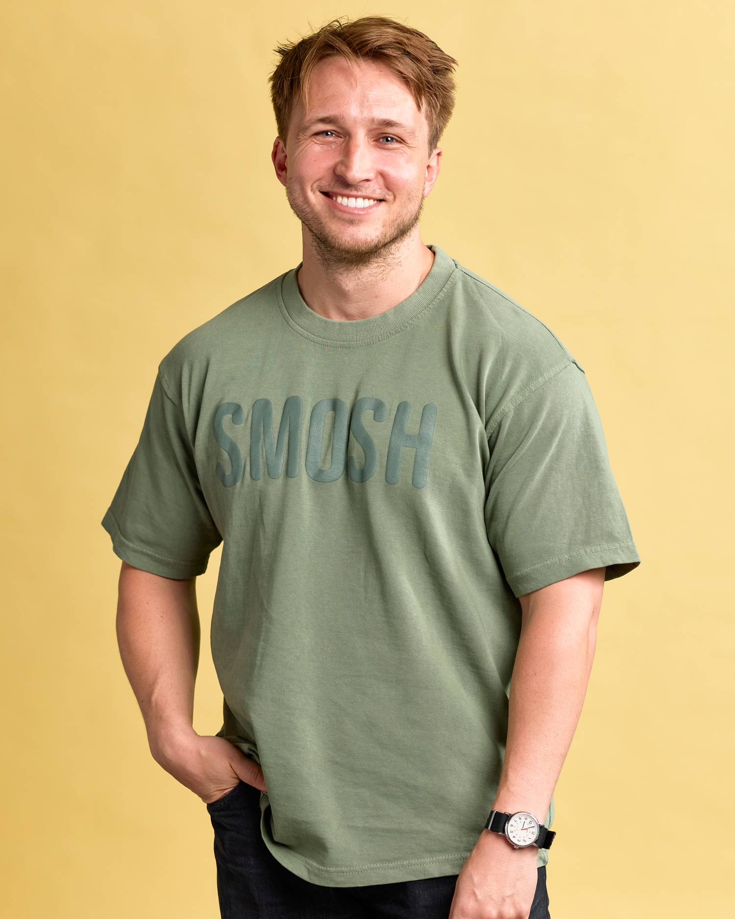 Man wearing a green 'SMOSH' t-shirt against a yellow background