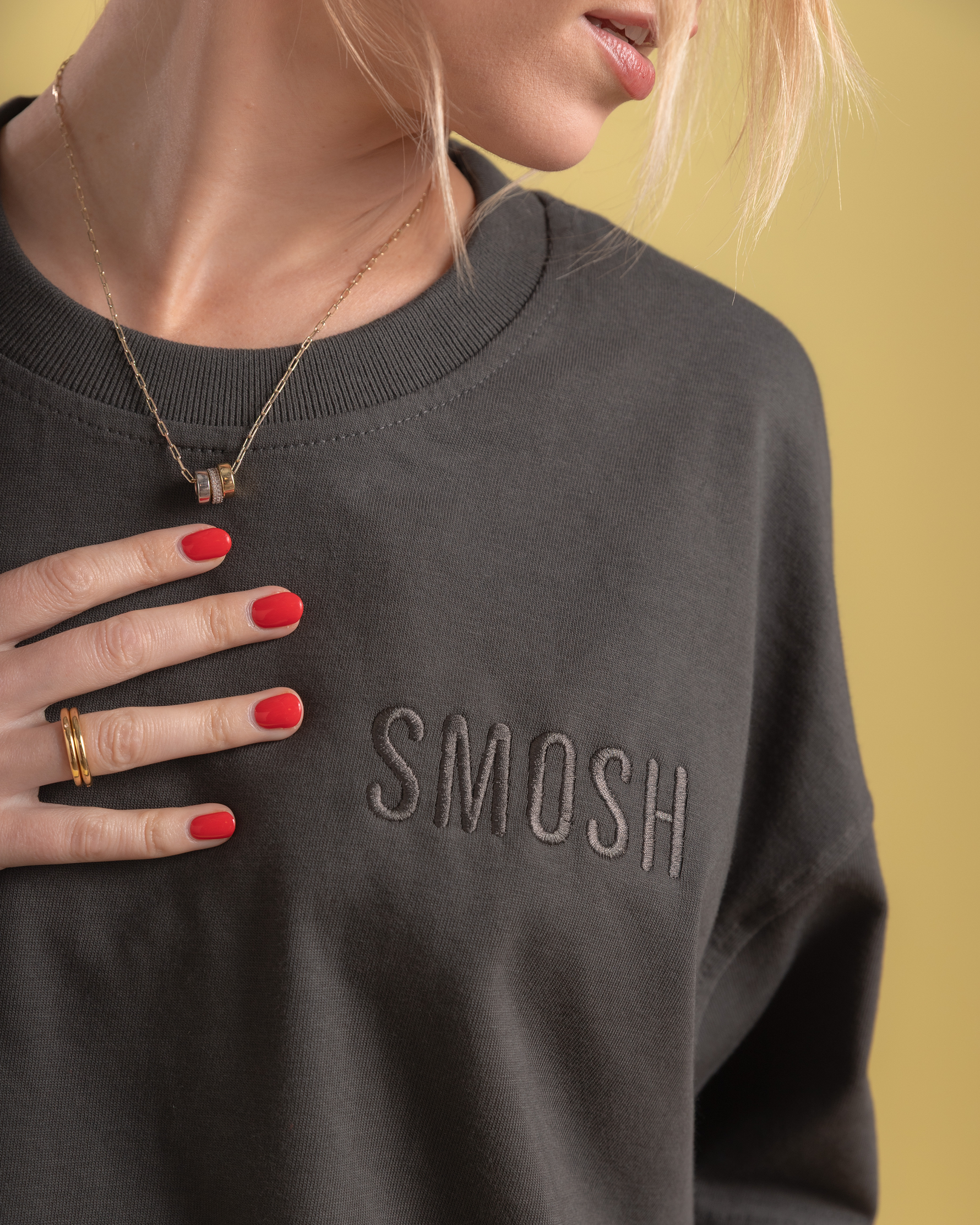 Person wearing a dark gray sweatshirt with 'SMOSH' text, against a yellow background