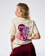 Woman wearing a cream t-shirt with 'SMOSH' text and stars on a white background back of shirt has a claw machine 