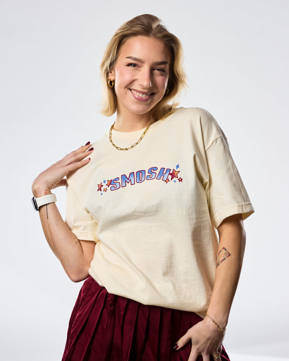 Woman wearing a cream t-shirt with 'SMOSH' text and stars on a white background