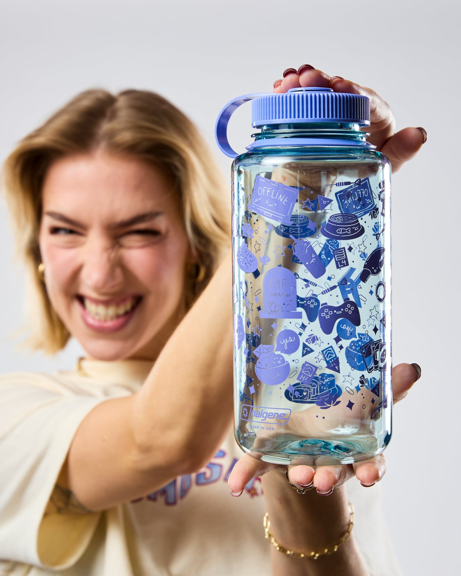 Person holding a blue water bottle with stickers, smiling against a white background