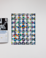 Notebook with colorful CD designs on a white surface next to a calendar.