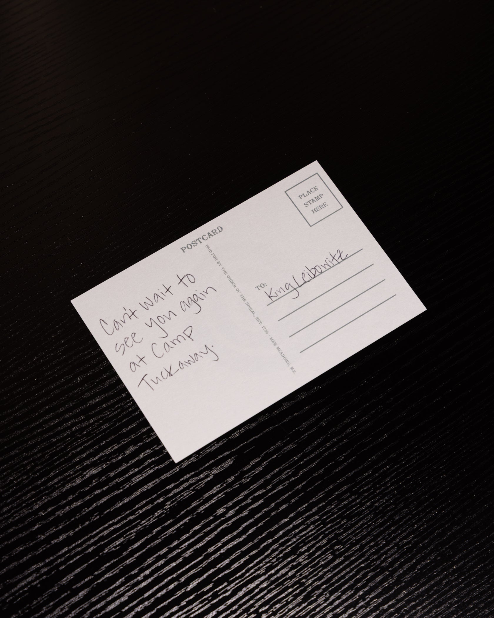 White postcard with handwritten text on a textured black surface